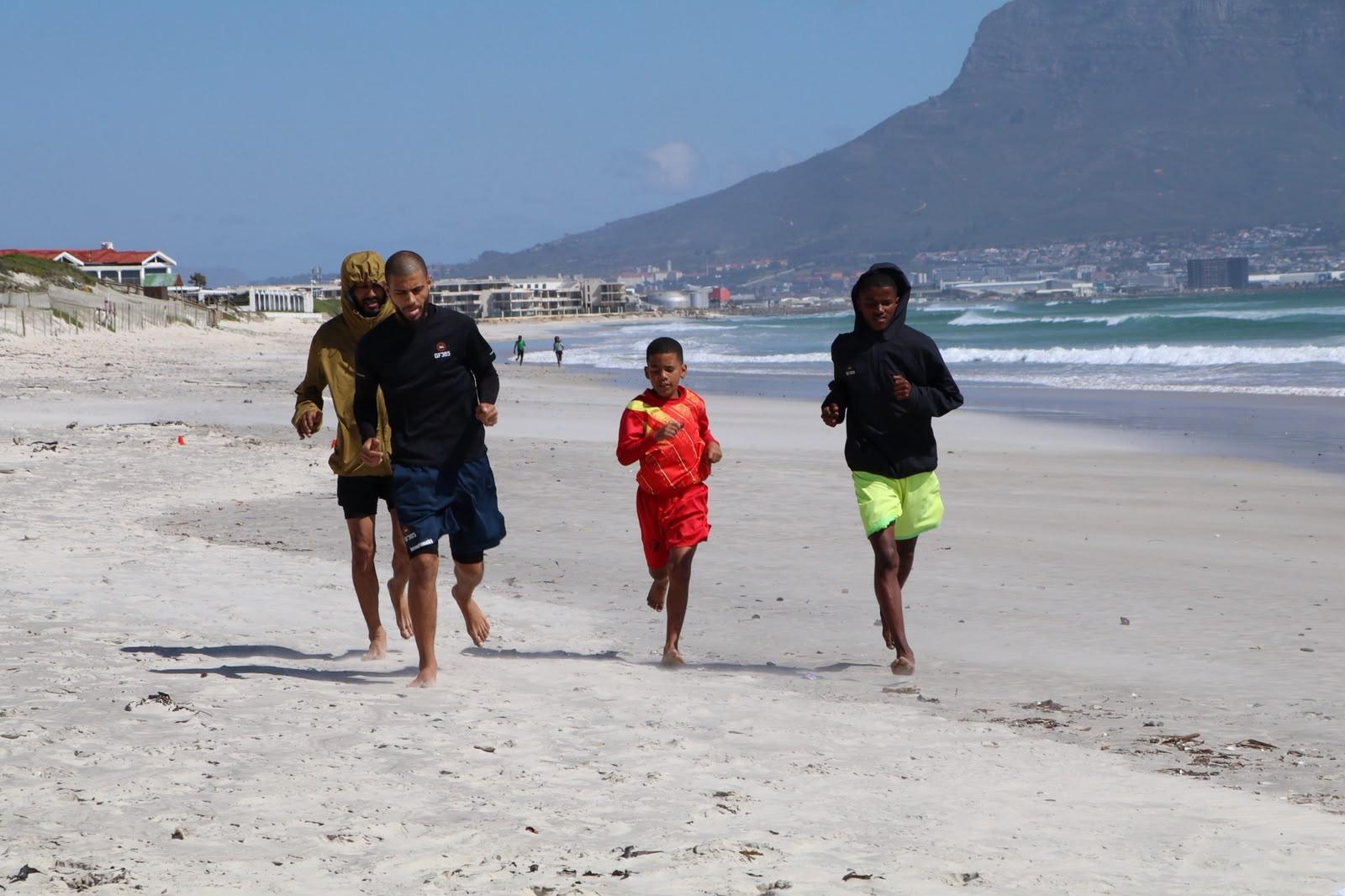 Coach and athletes running on the beach