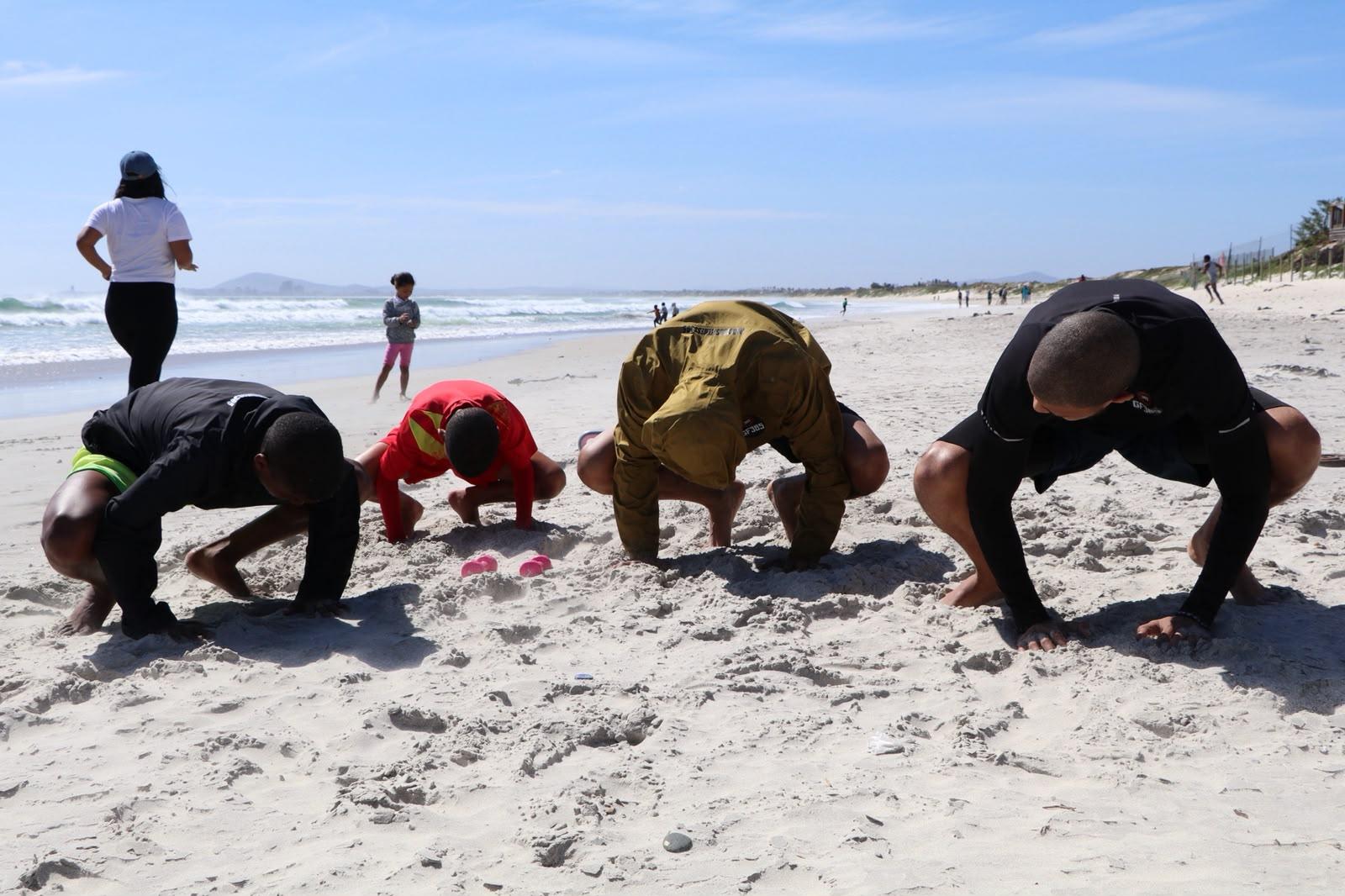 Beach session, athletes in a bear crawl