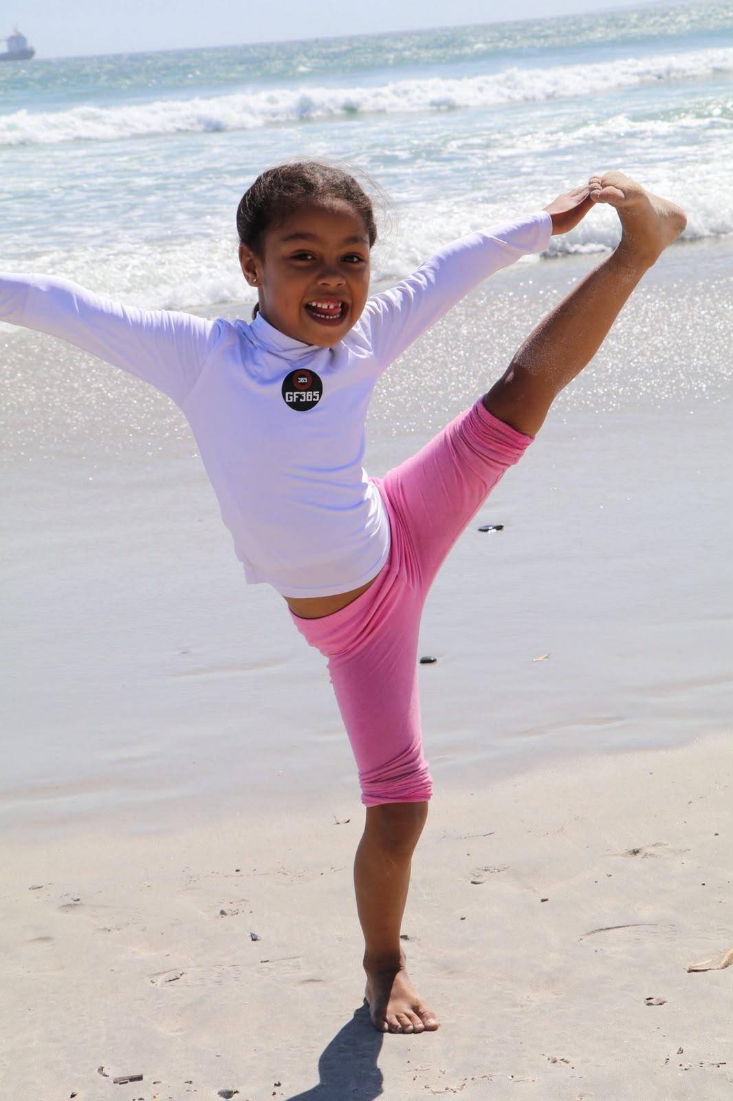 Young athlete holding a standing kick on the sand