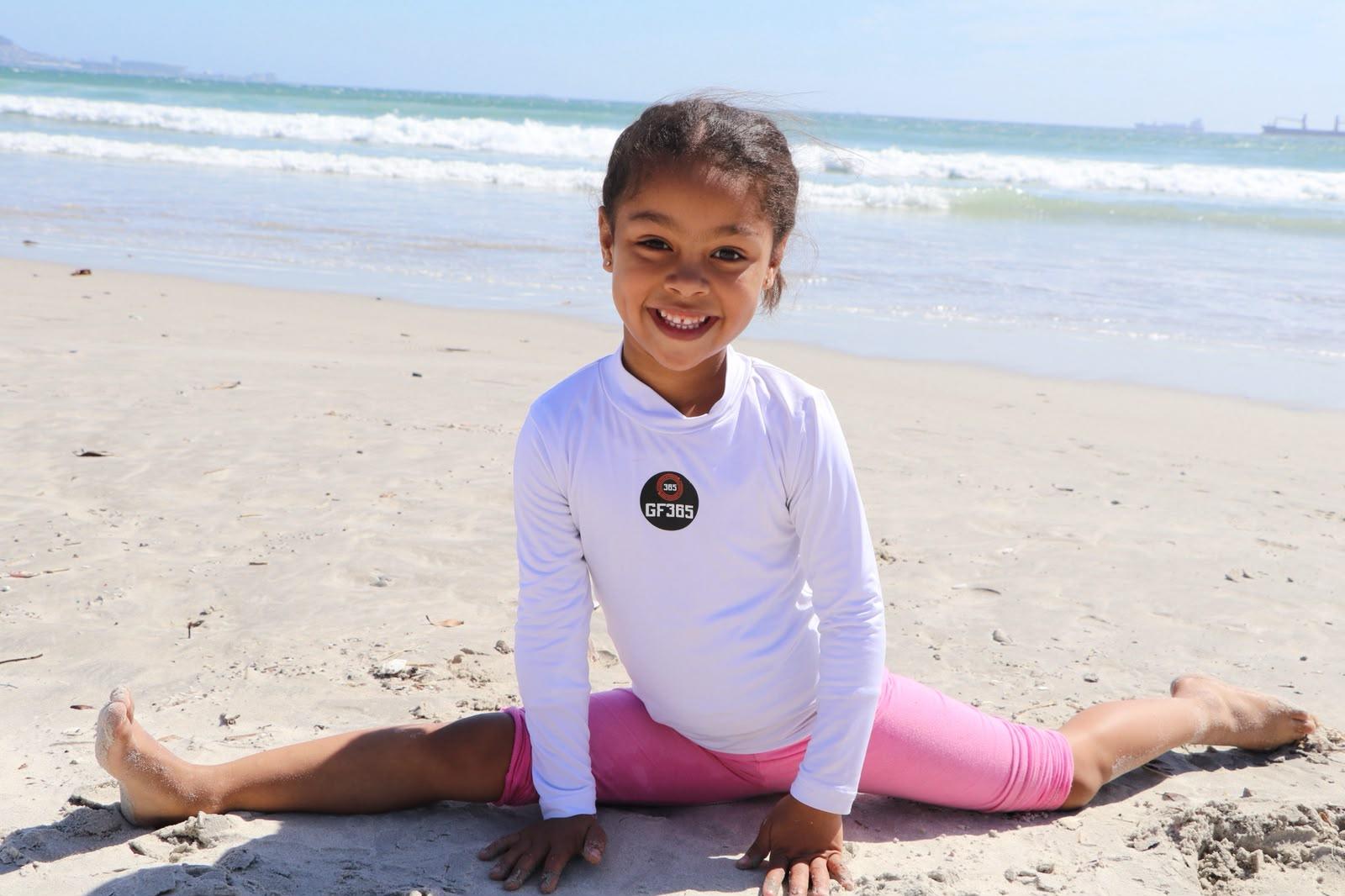 Young athlete smiling in a split on the beach